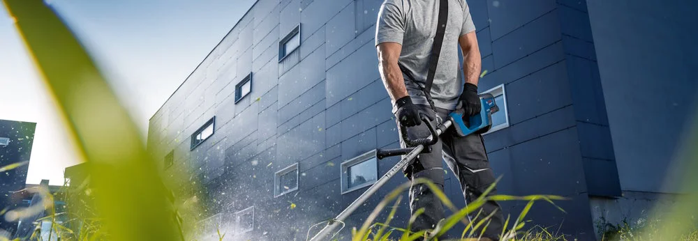 Person trimmt Gras mit Rasentrimmer